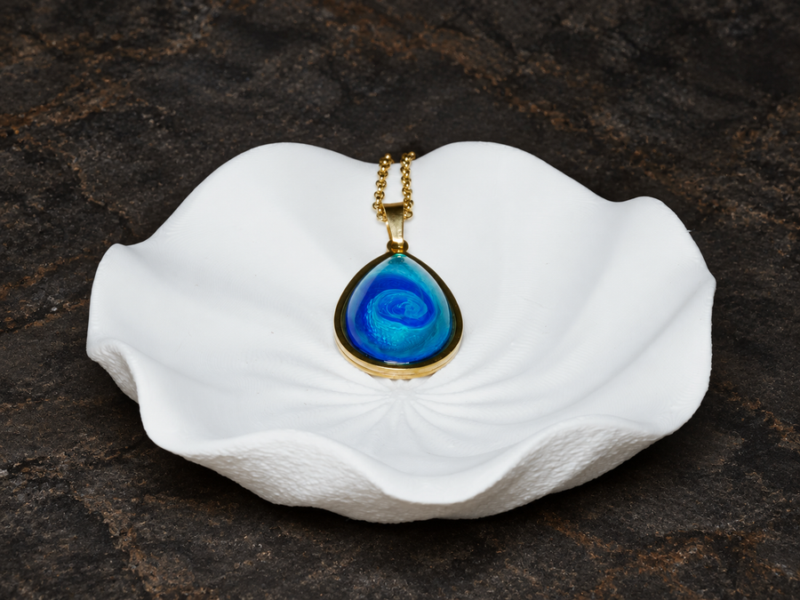 Abyssal Current blue teardrop pendant displayed on a sculptural form