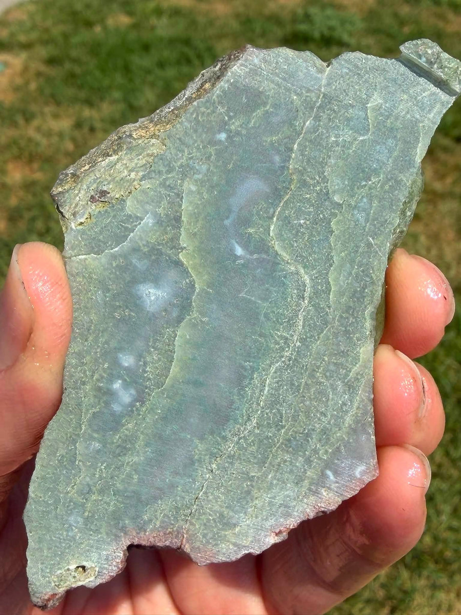 Supplier photograph of a green moss agate slab, wet outdoor view