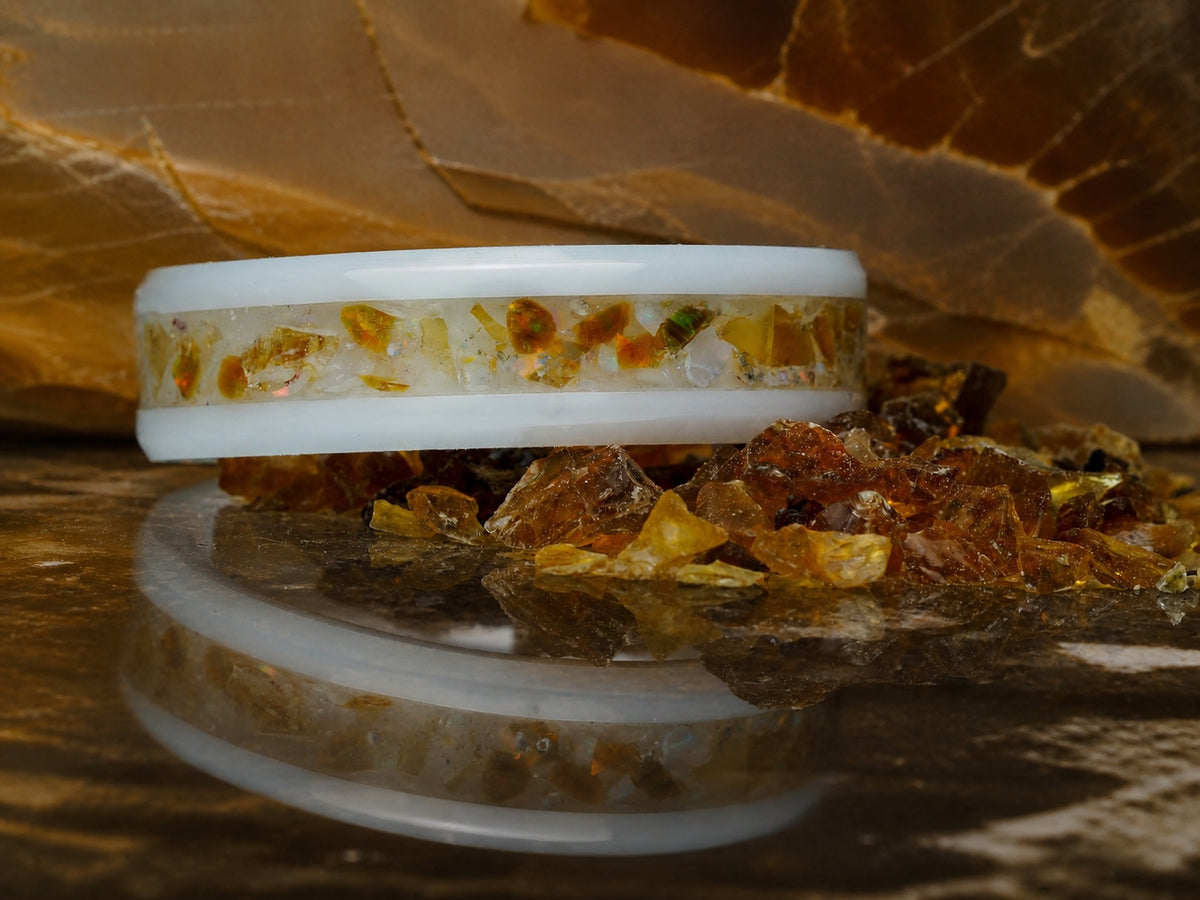 Resin of Time: Afterglow ring resting on amber fragments with a mirrored reflection
