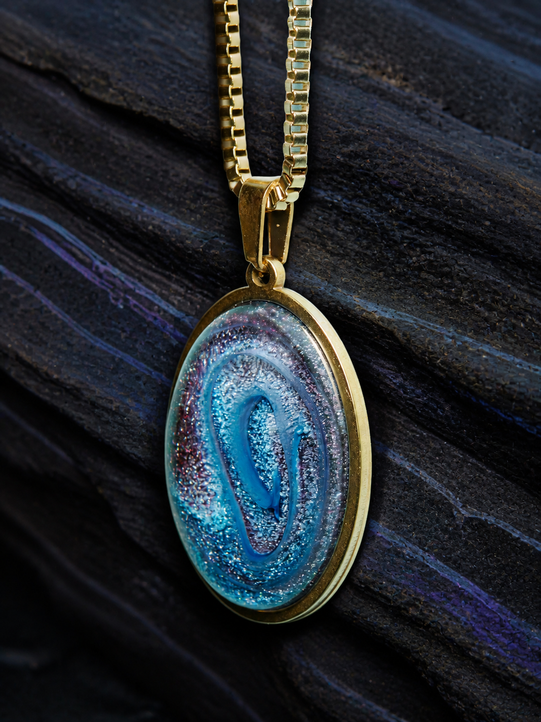 Close portrait of the Abyssal Spiral oval pendant in an 18k gold plated bezel