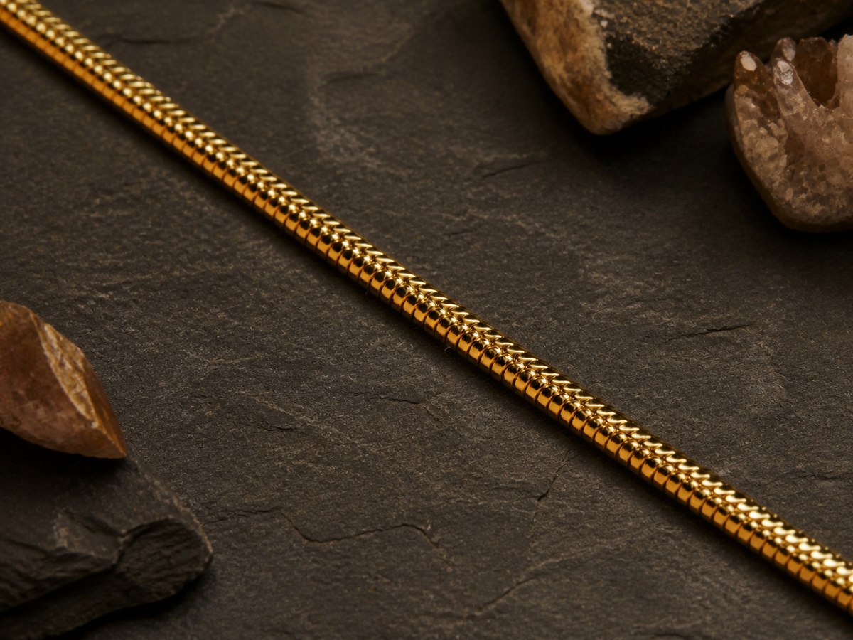 Detail of the 18k gold plated snake chain on a mineral background
