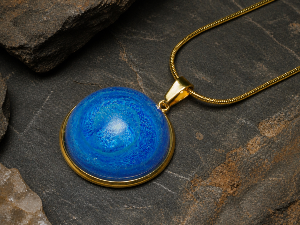 Blue resin round pendant and 18K gold-plated snake chain on quartz-like stone