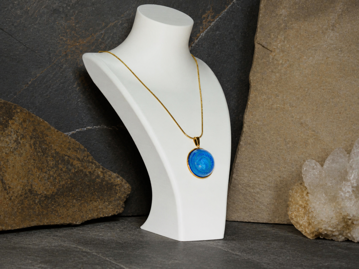 Round blue resin necklace on angled display bust with geological background