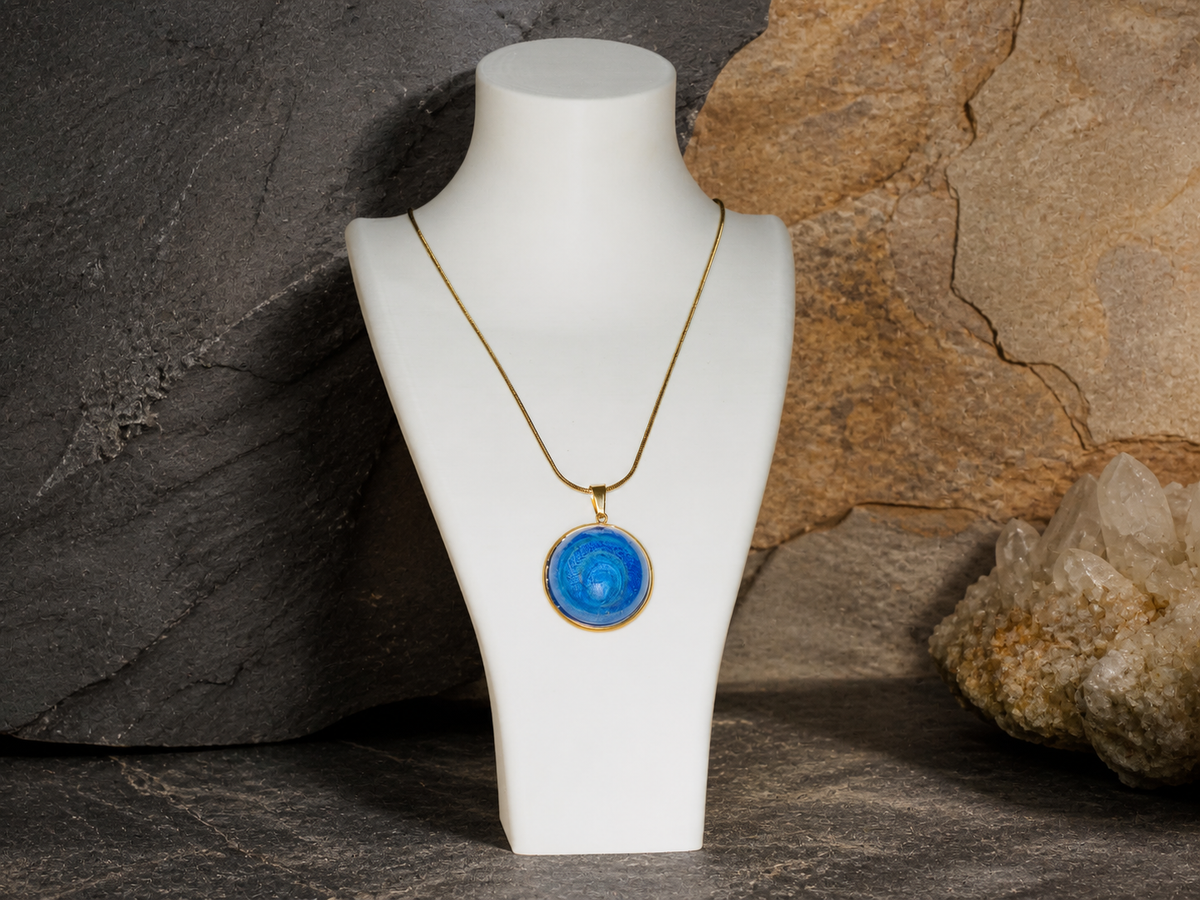 Round blue resin pendant and chain in close-up on mineral texture