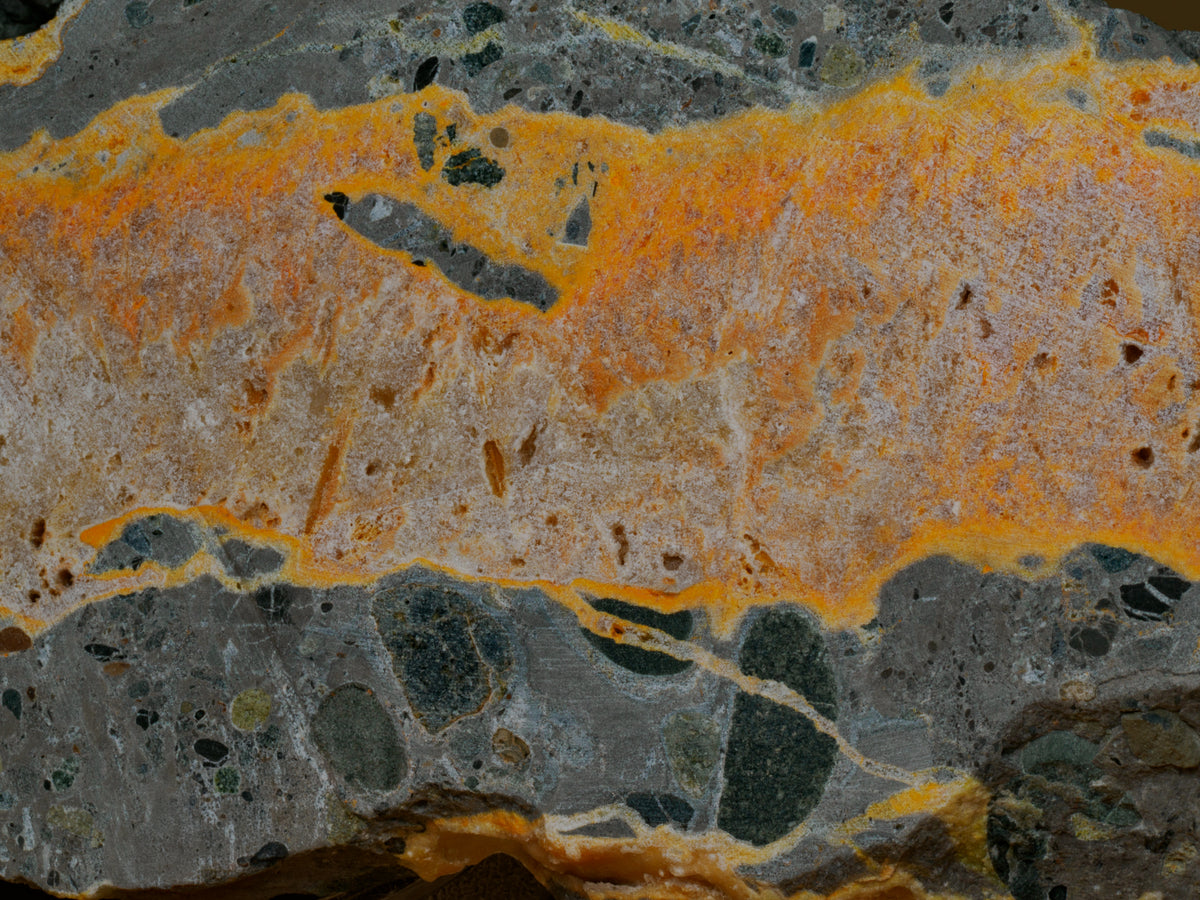 Close view of the bumblebee jasper slab showing orange and cream banding against dark grey stone