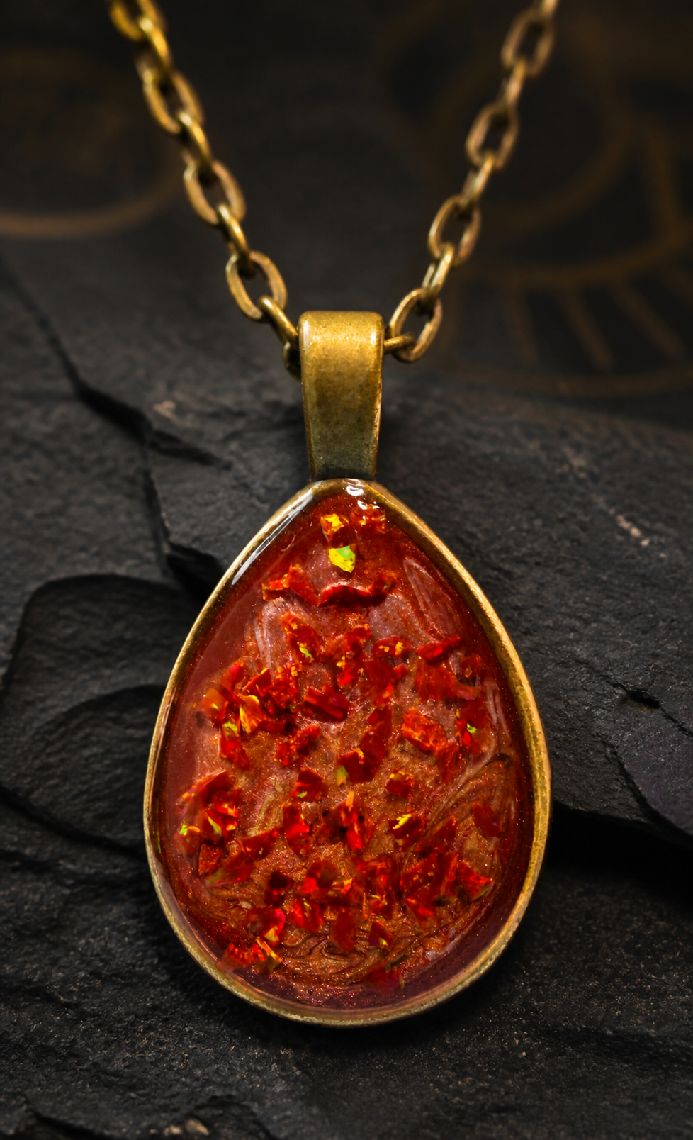 Front macro view of the Cinderstrata red opal-style pendant on dark mineral stone