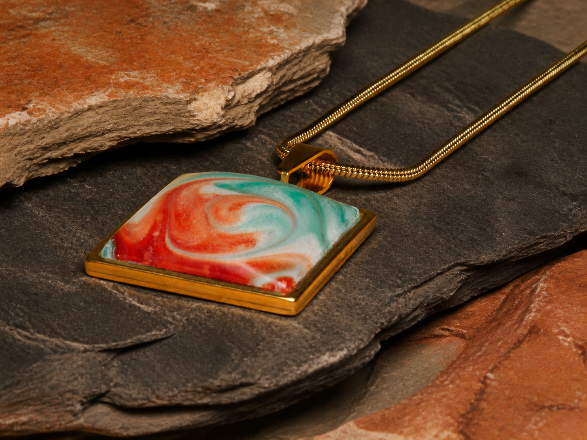 Square gold-plated pendant with turquoise and coral resin artwork on layered slate