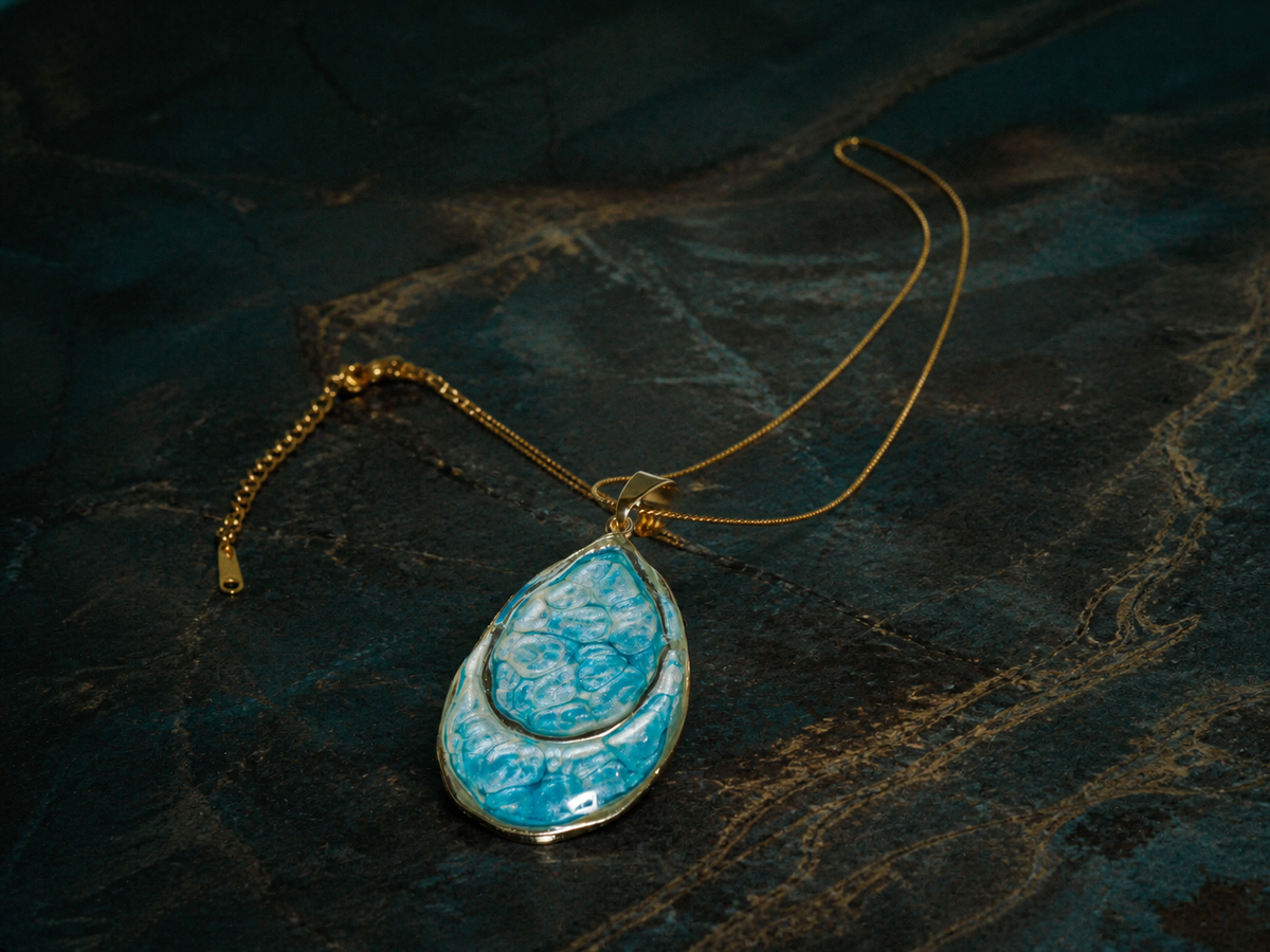 Double teardrop pendant and fine gold-plated chain on a mineral surface