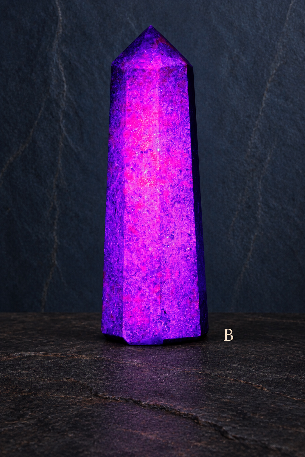B UV-lit ruby in kyanite obelisk labelled B against a slate gallery background