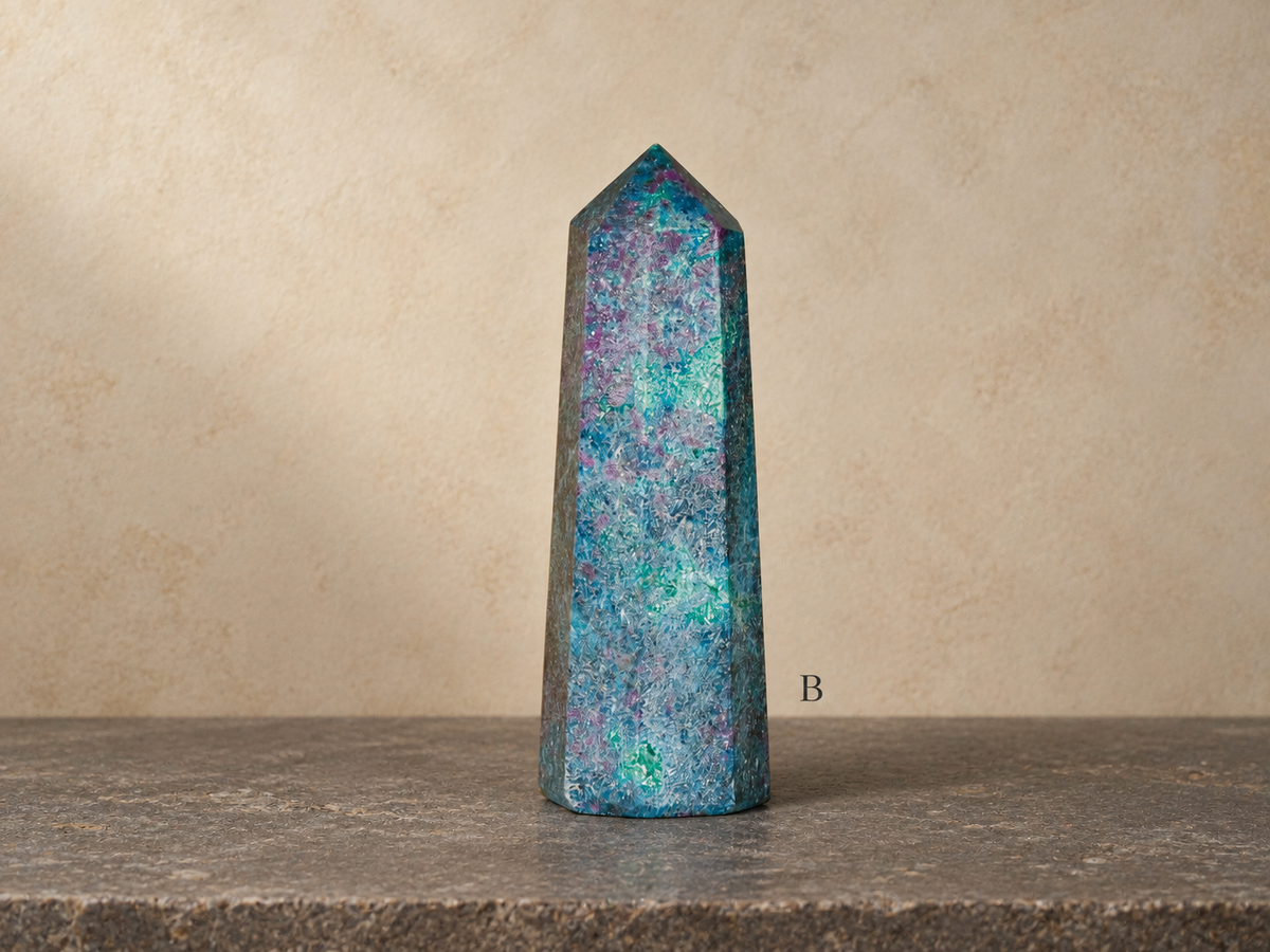 B ruby in kyanite obelisk in natural light, labelled B against a warm parchment gallery background