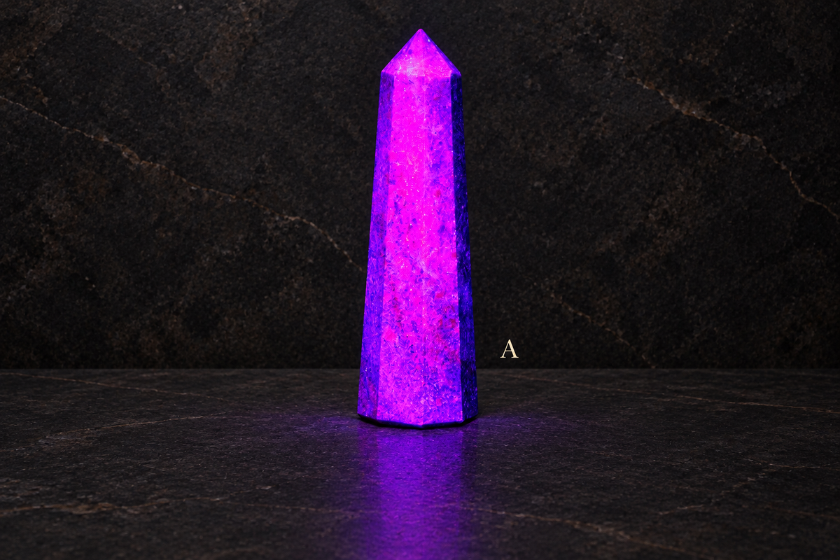 A UV-lit ruby in kyanite obelisk labelled A against a dark limestone gallery background