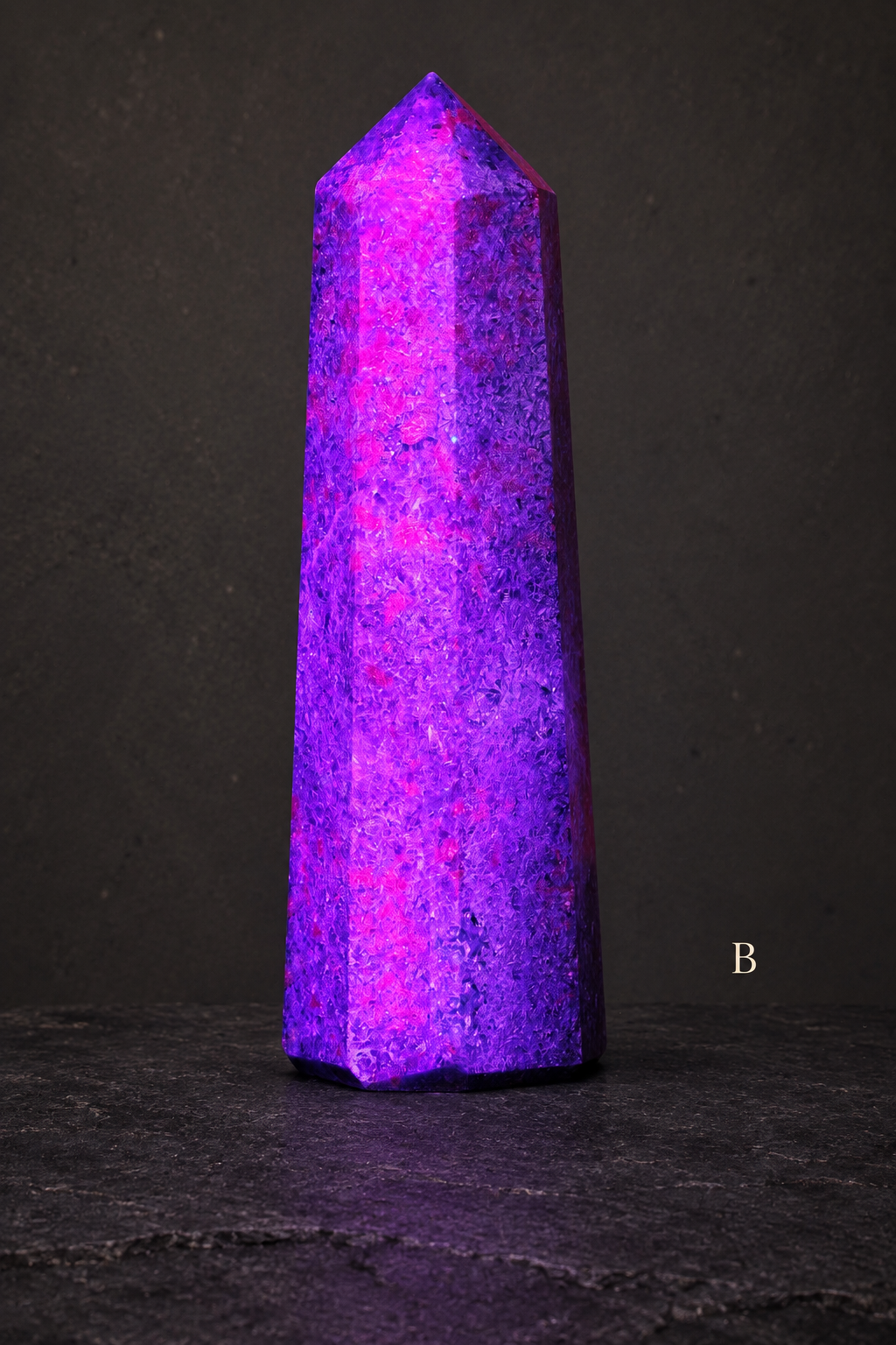 B UV-lit ruby in kyanite obelisk labelled B against a charcoal gallery background