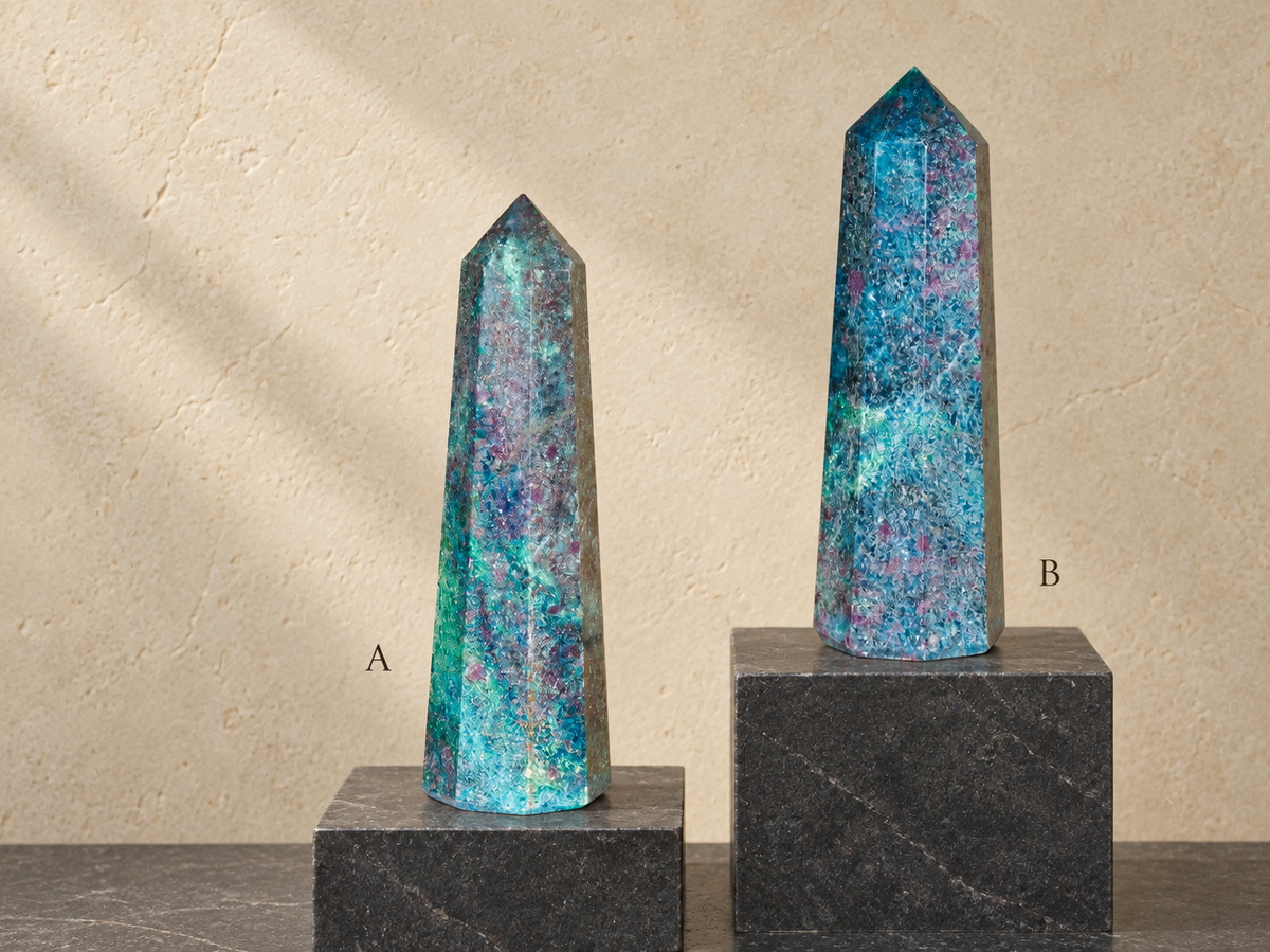 Ruby in kyanite obelisks A and B in natural light on digitally staged stone plinths; A slender at left, B broader at right