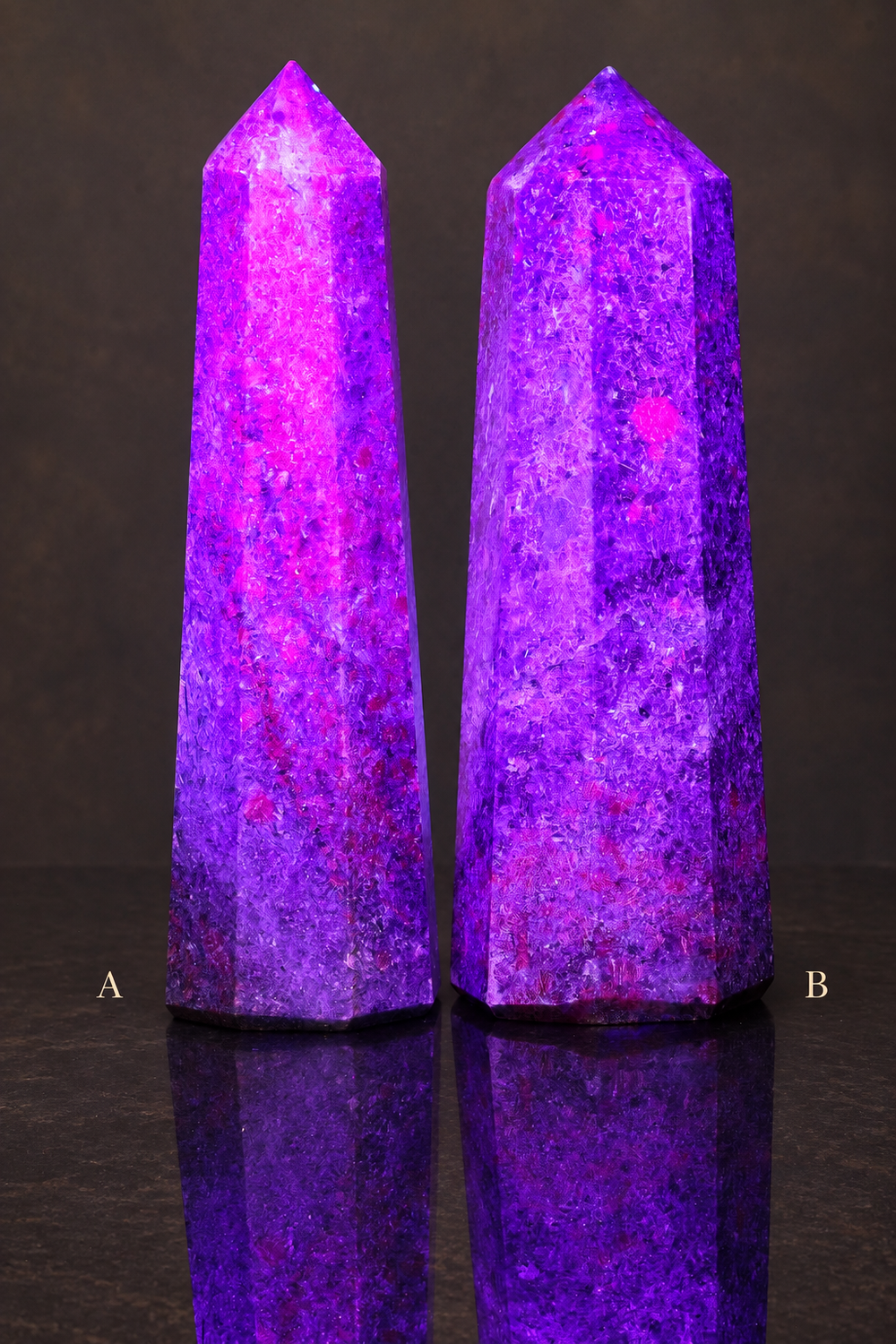 Ruby in kyanite obelisks under UV light; slender A left and broader B right, on a dark gallery background