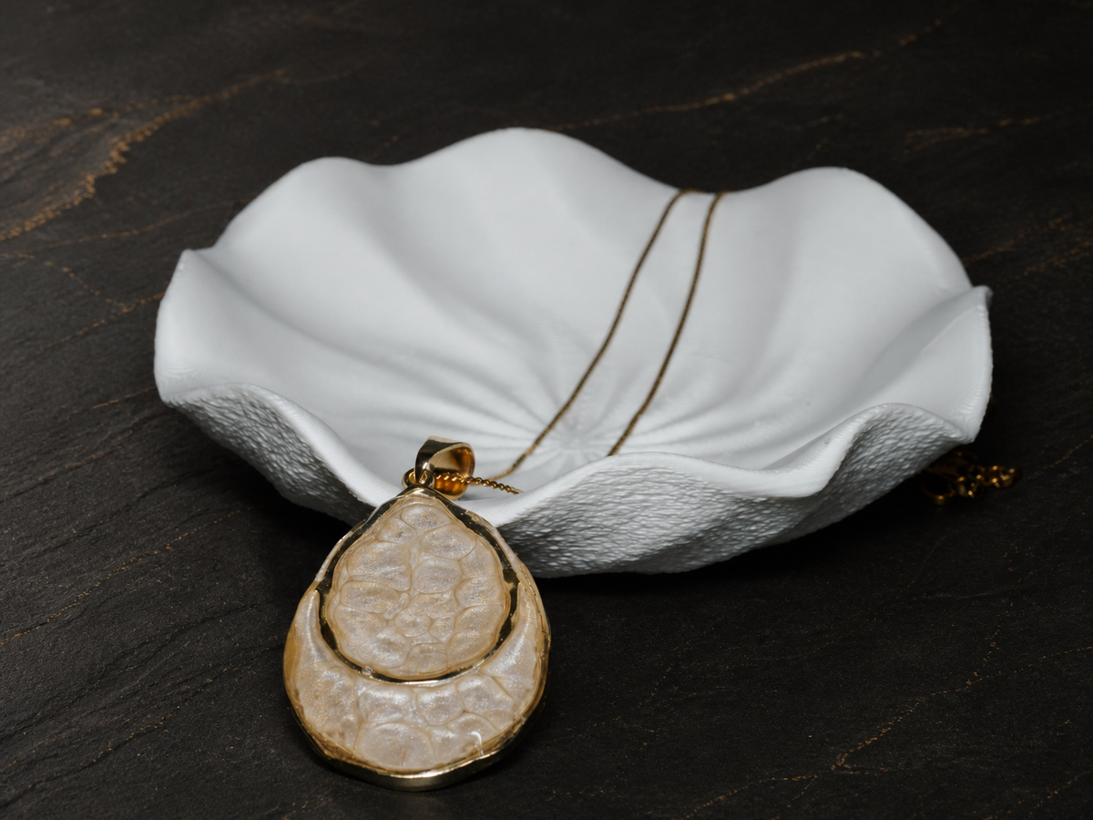 Earthlight Strata hand-painted pendant beside a sculptural white dish