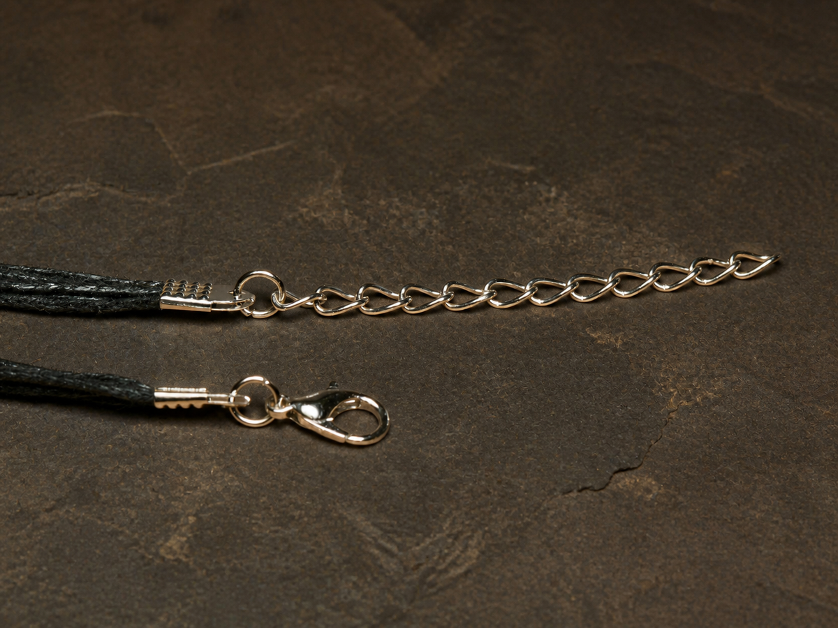 Black five-string necklace and silver extension chain for the Ember Tide pendant on dark mineral stone