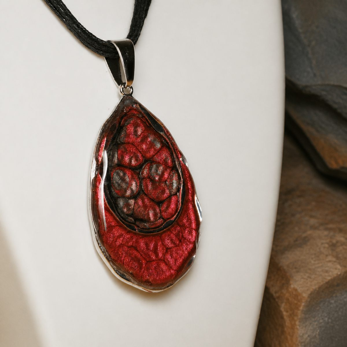 Close-up of the red enamel paint art and resin-coated silver double-teardrop pendant