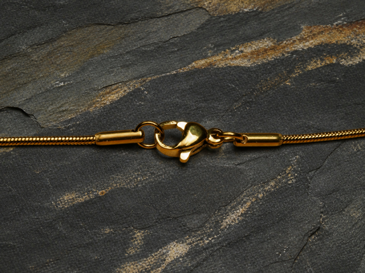 Gold-plated stainless steel snake chain clasp on layered slate and sandstone
