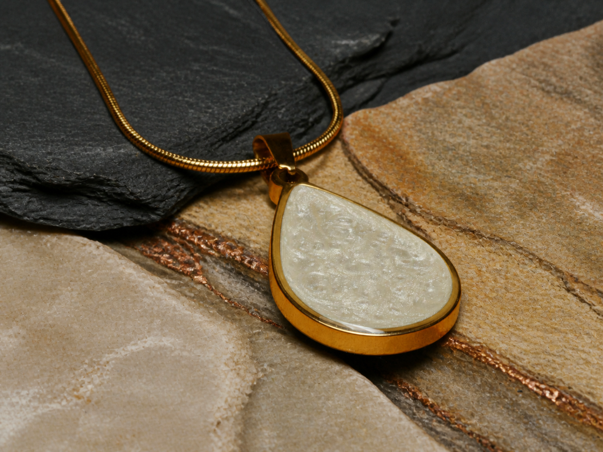 Teardrop gold-plated pendant with pearlescent ivory resin artwork on layered slate