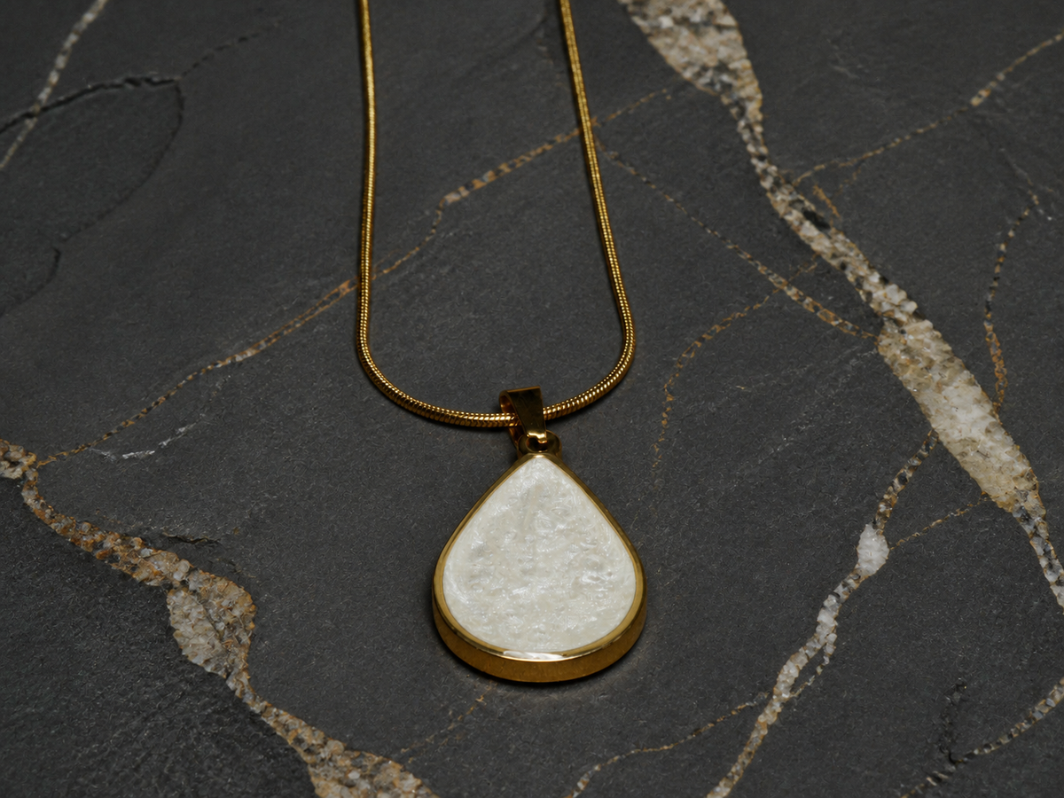 Hanging teardrop pendant and 55cm gold-plated snake chain on geological stone