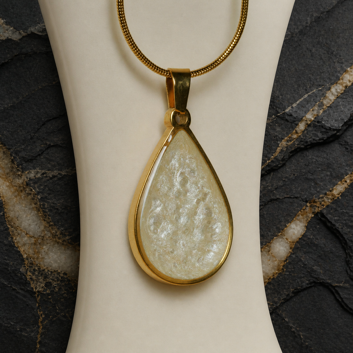 Close-up of pearlescent golden ivory teardrop pendant on a necklace bust