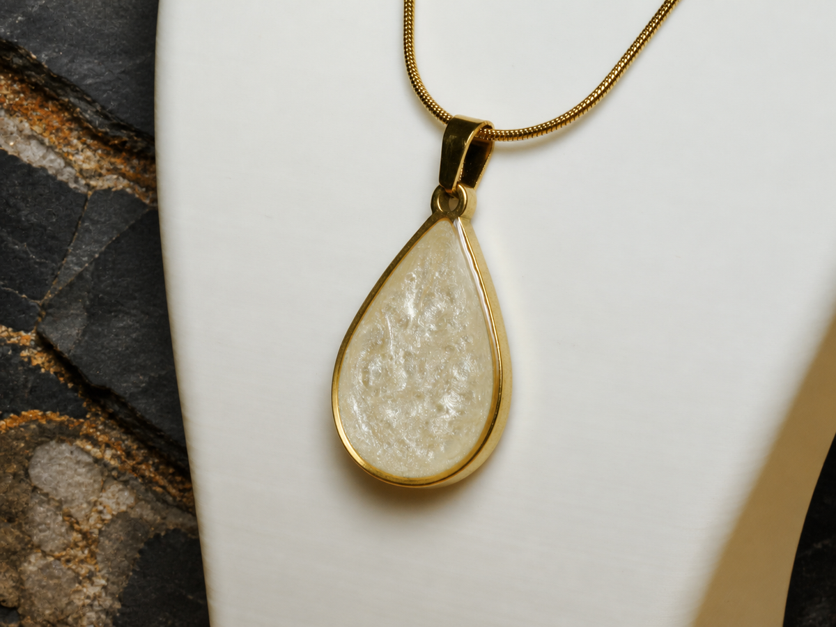 Close-up teardrop pendant with clear resin surface on a white necklace bust