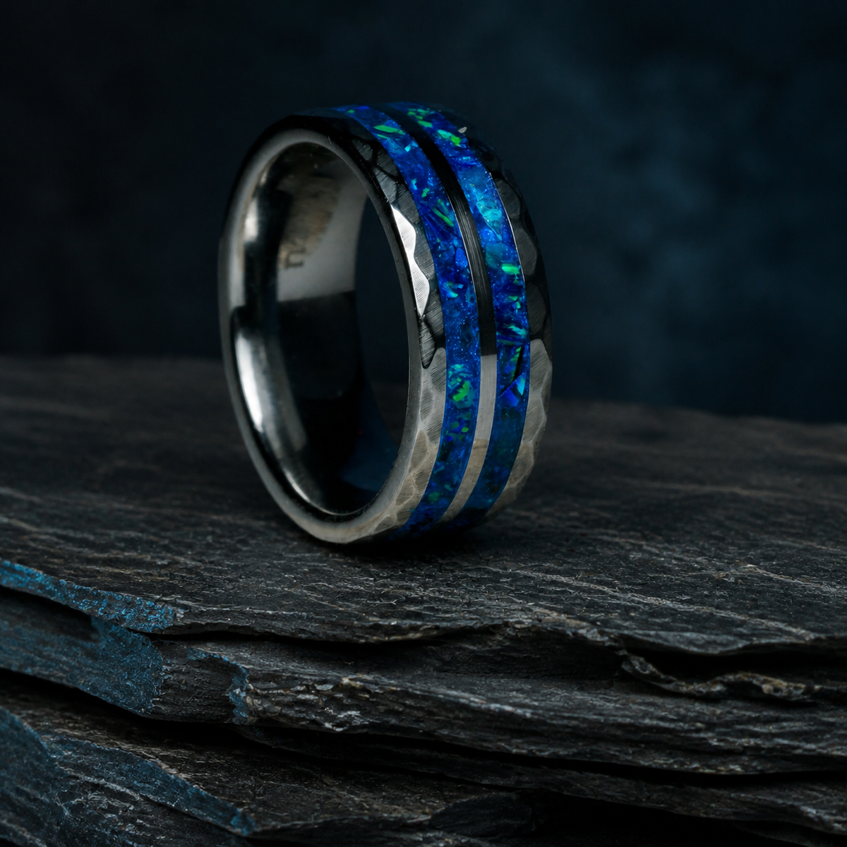 Angled Neptune’s Anvil tungsten ring with luminous blue mineral inlay on dark geological stone