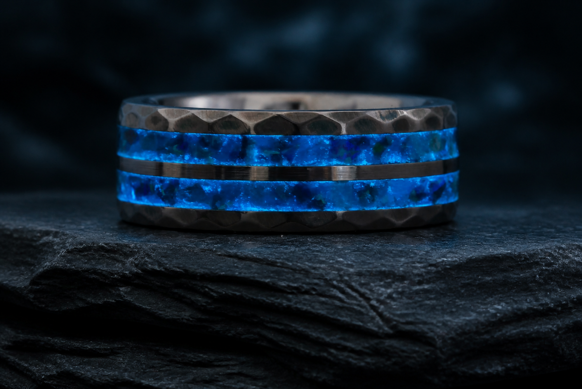 Neptune’s Anvil ring glowing with blue mineral inlay on a dark layered stone display