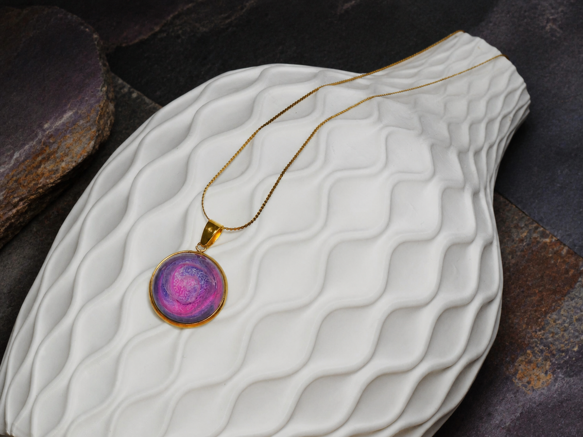 Rose Tide Orbit round pendant necklace on a white textured display form with dark geological stone