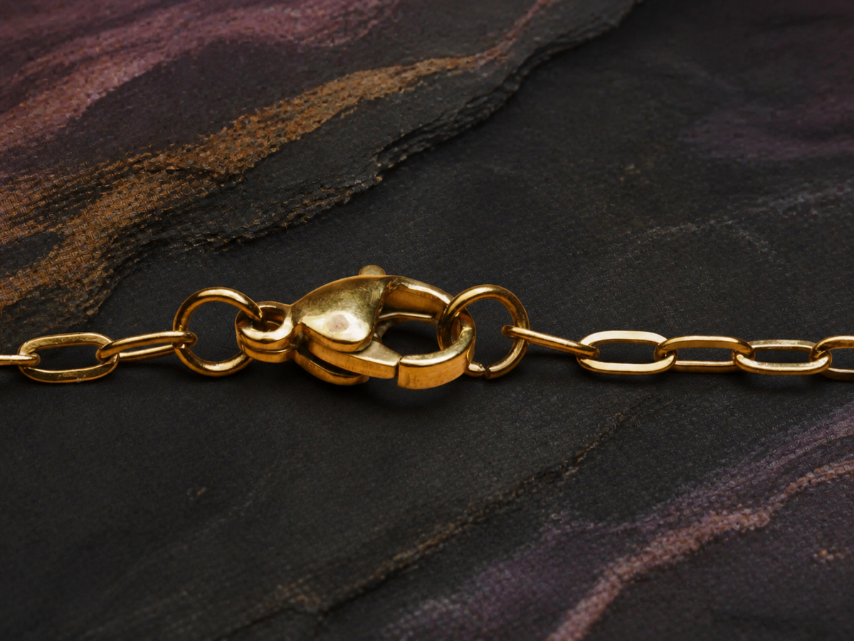 Fine gold chain clasp detail for the Rose Tide Orbit necklace on dark mineral stone