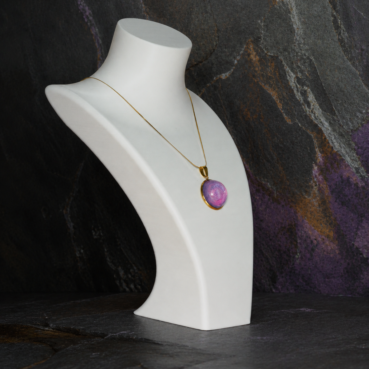 Rose Tide Orbit round pendant necklace on a white display bust against dark mineral stone