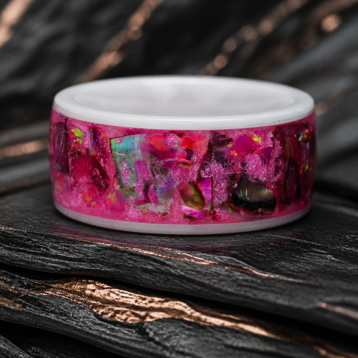 Close-up of the Rosetide Lumina pink iridescent ring on dark slate