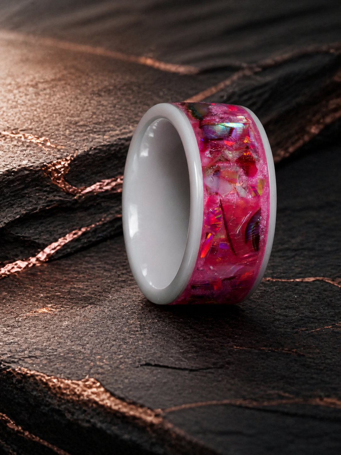 Three-quarter view of the Rosetide Lumina white ceramic ring on dark geological stone