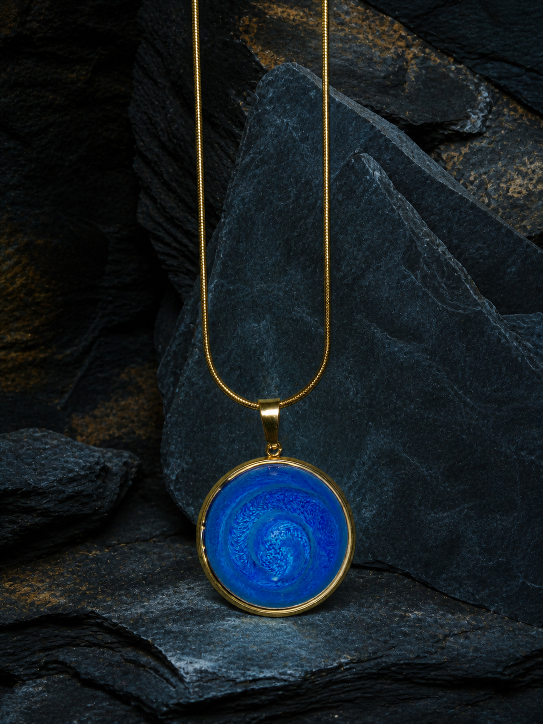 Full Tethys Gyre pendant necklace displayed against blue-grey slate and charcoal shale