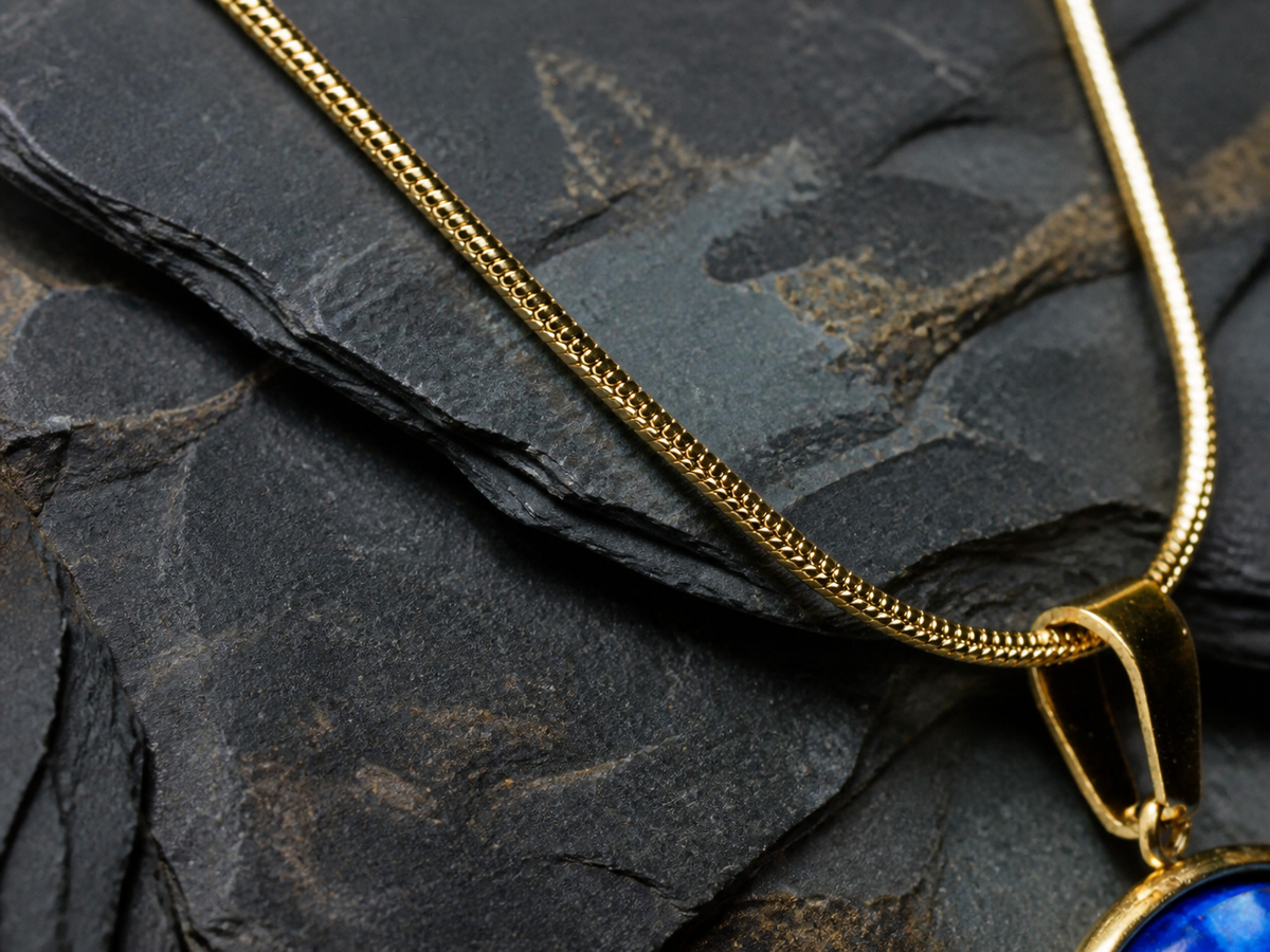 Detail of the 18K gold-plated snake chain and pendant bail on layered dark stone