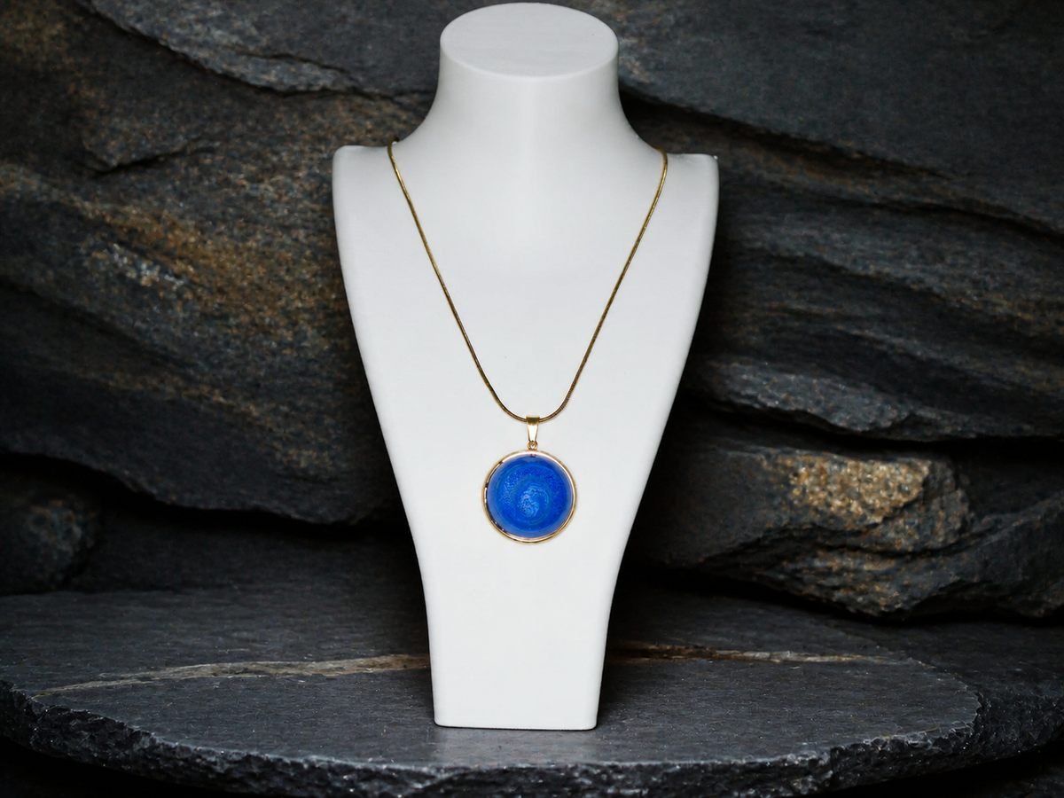 Tethys Gyre pendant necklace shown at full length on a display bust with a stratified rock background