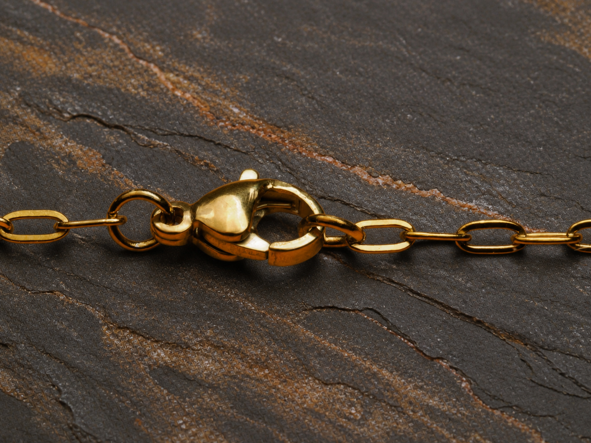 Gold-plated chain clasp on layered basalt with copper mineral seams