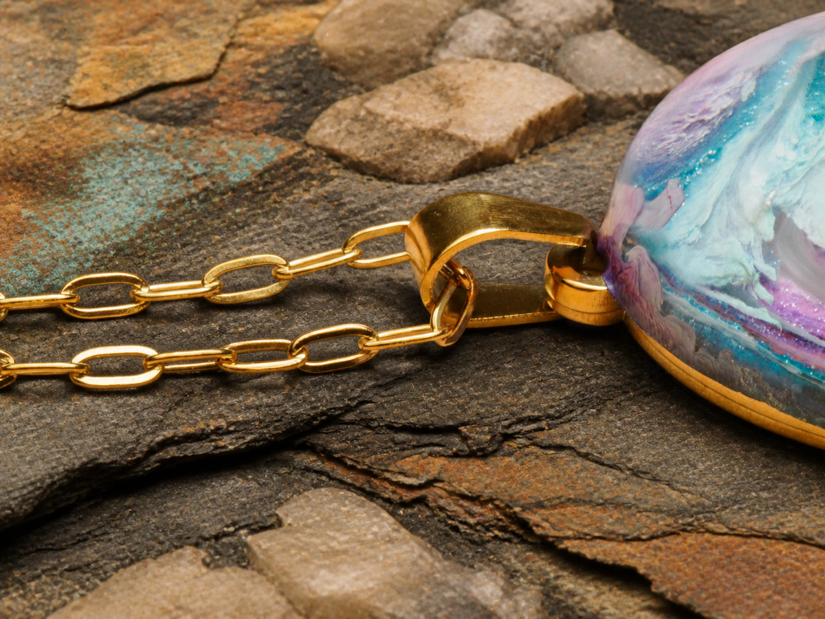 Gold-plated chain, bail and partial oval pendant on layered slate and sandstone