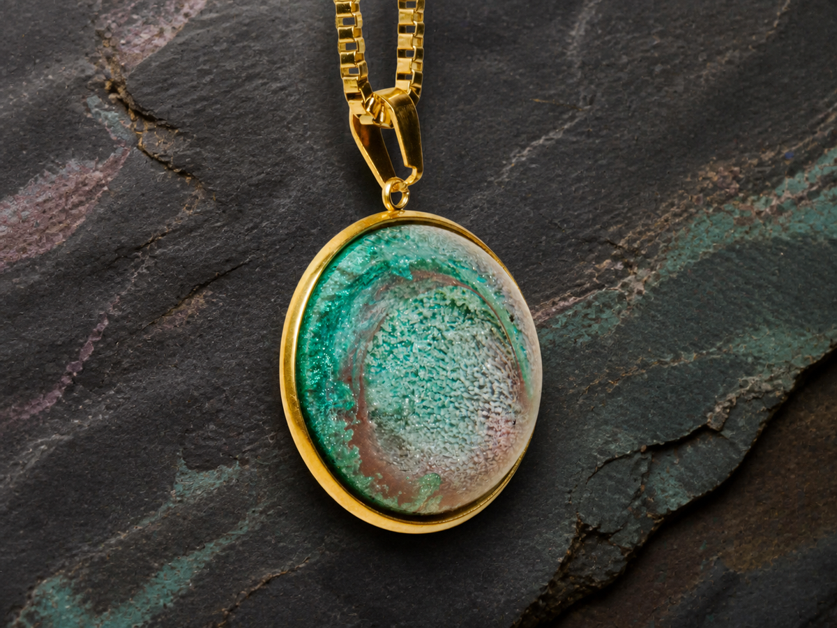 Angled close-up of the Tidal Patina gold pendant, bail and box chain