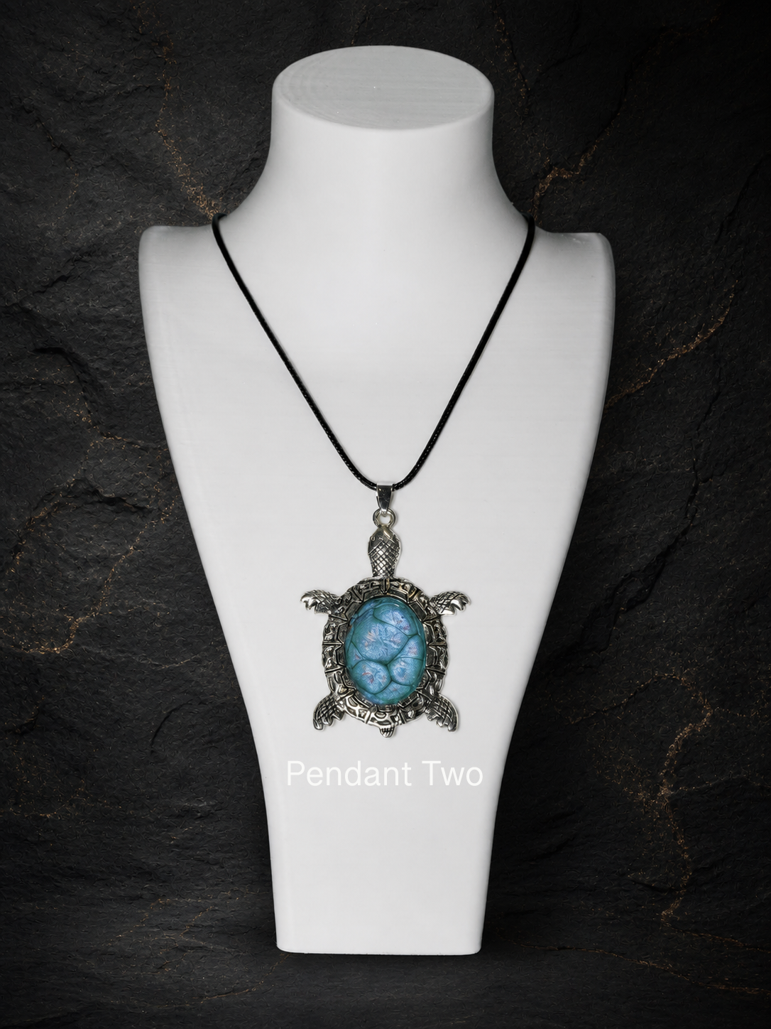 Pendant Two silver turtle pendant worn on a black cord necklace
