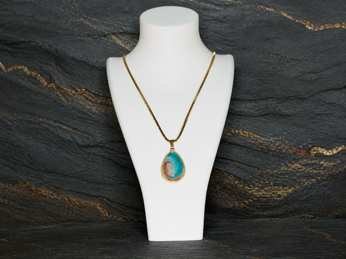 Tidal Rift 18K gold-plated teardrop pendant on a charcoal geological slate background