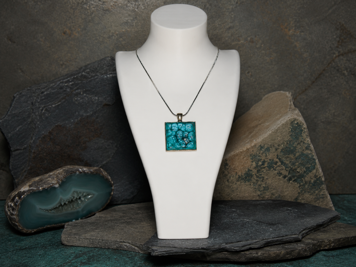 Silver square pendant and 45cm silver plated chain displayed on a necklace bust with rocks