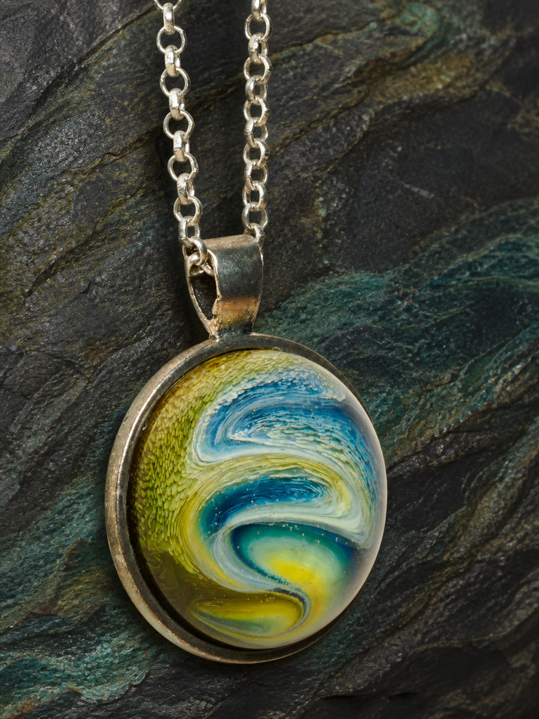 Detailed vertical view of the Verdant Gyre silver pendant, bail and chain
