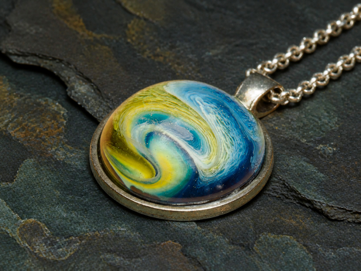 Macro view of the Verdant Gyre pendant artwork, silver bail and chain on dark mineral stone