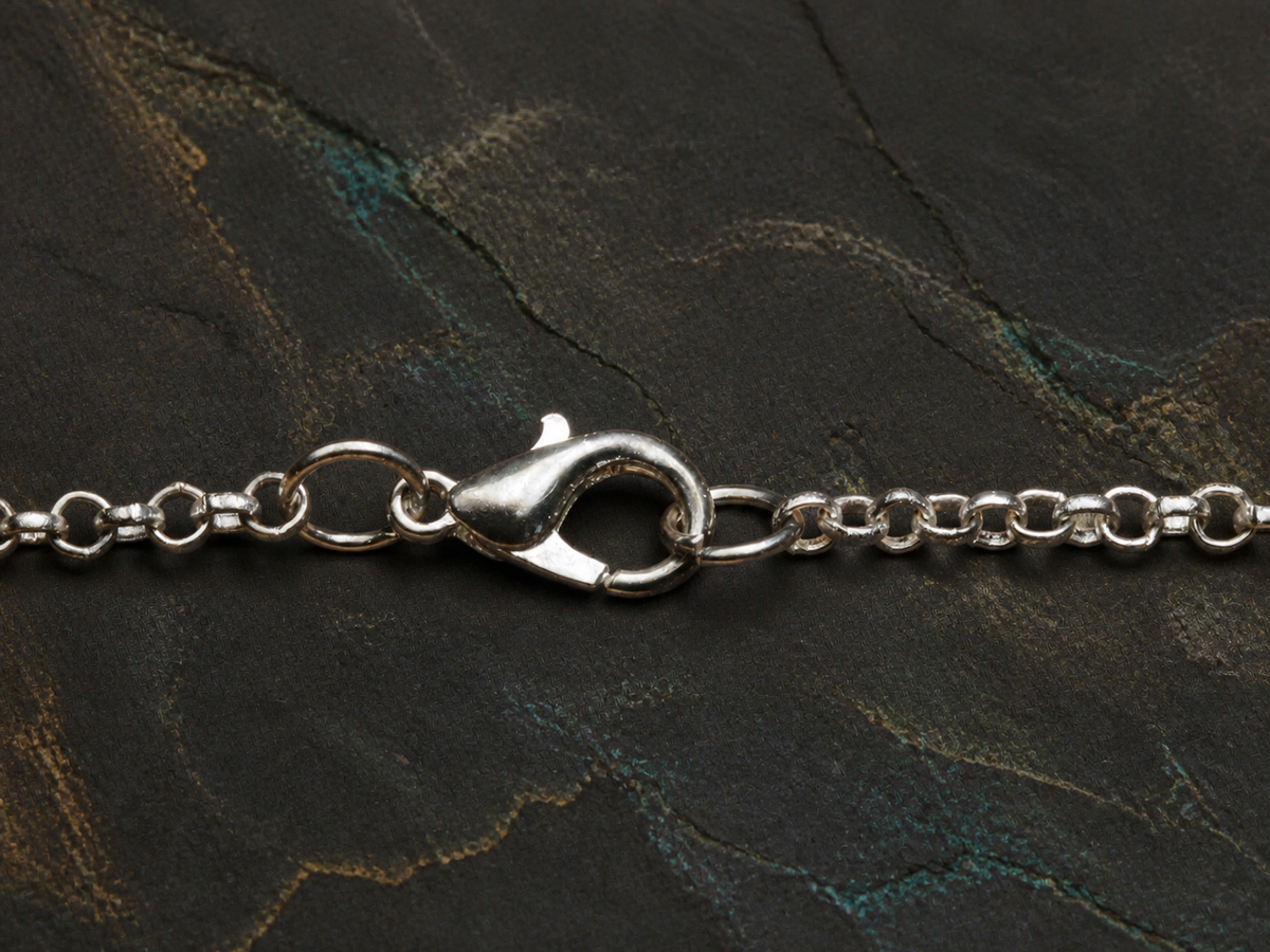 Silver chain clasp detail for the Verdant Gyre pendant necklace on dark slate