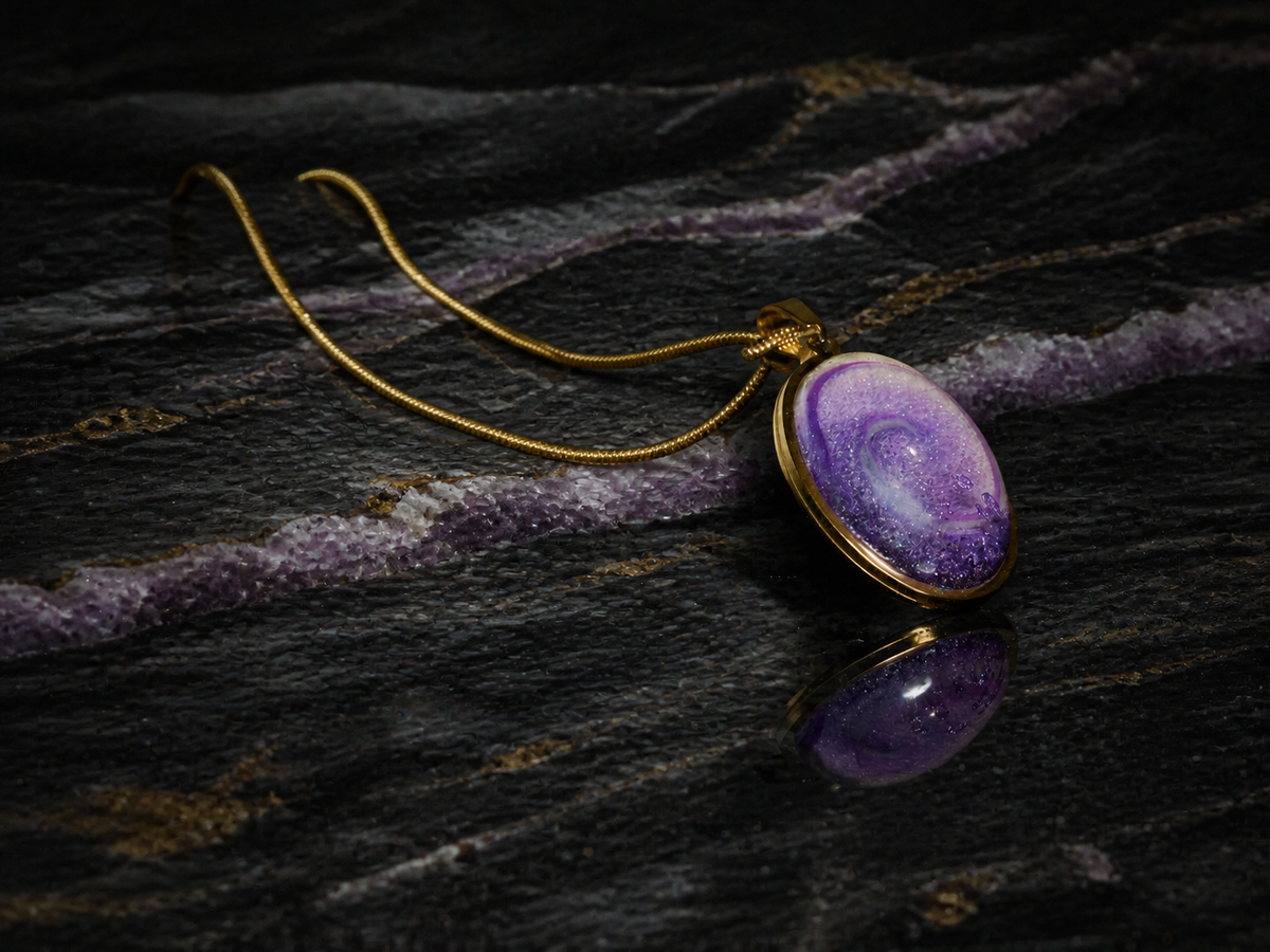 Violet Gyre pendant and gold snake chain on banded stone, wide view
