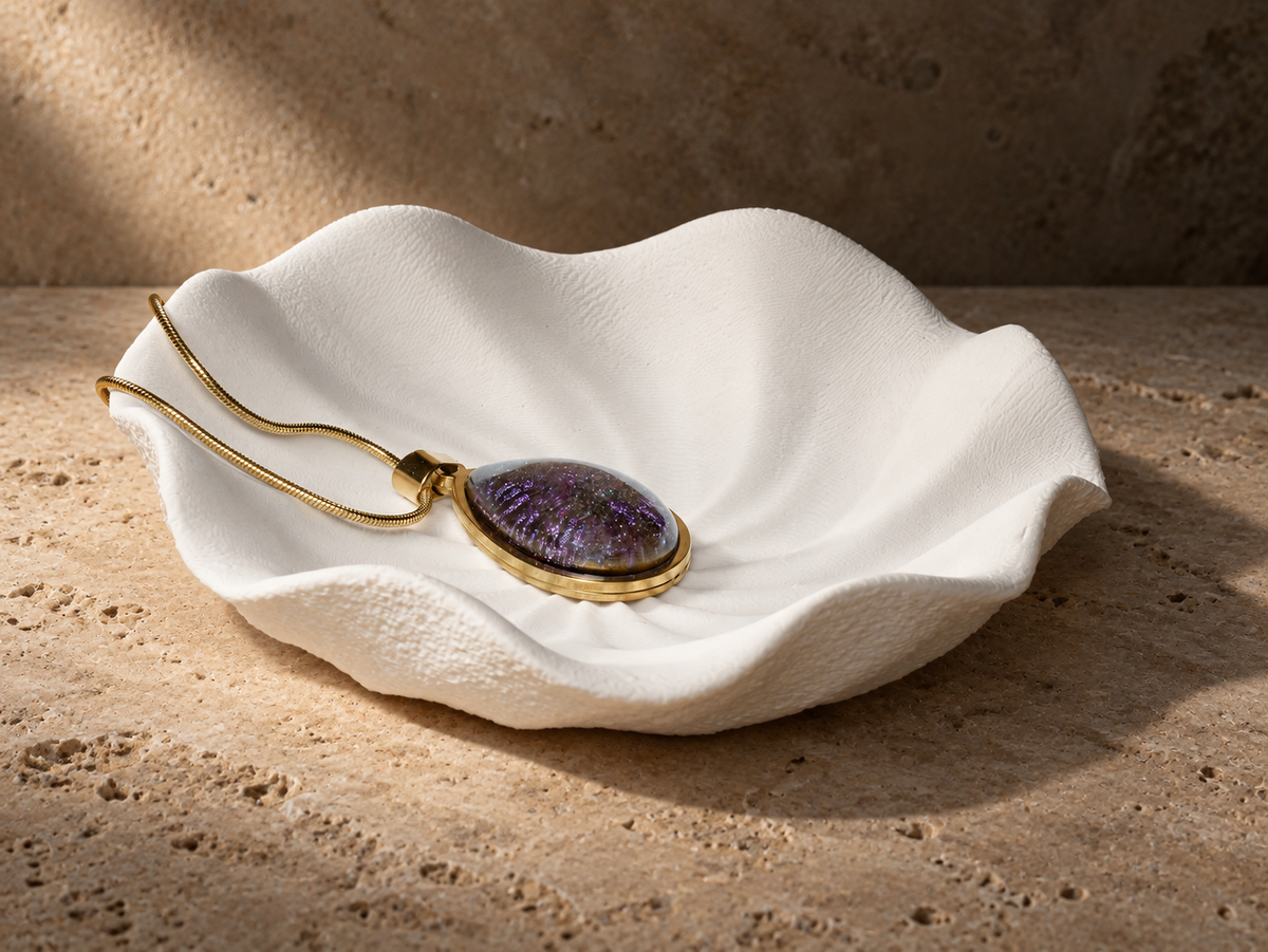 Violet Orbit pendant necklace resting on a sculptural shell form